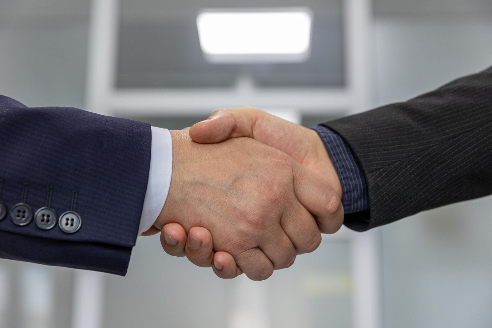 Two business partners shaking hands over a signed agreement
