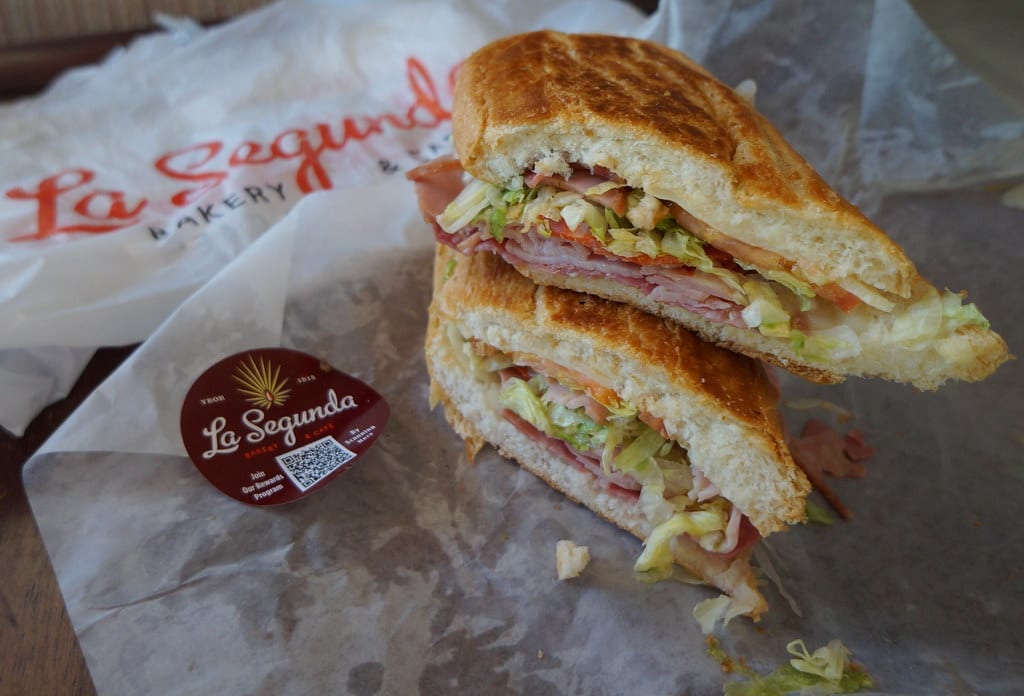 A finished submarine sandwich on a sub roll, sliced open to show layered meat and toppings