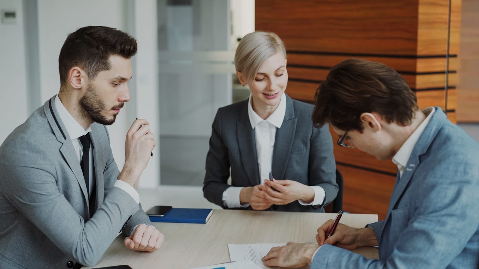 Business professionals reviewing and signing a contract at a table