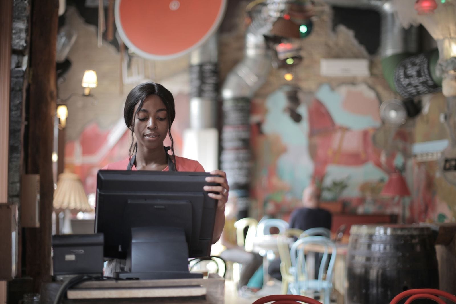 A restaurant employee operating a point-of-sale register at a service counter