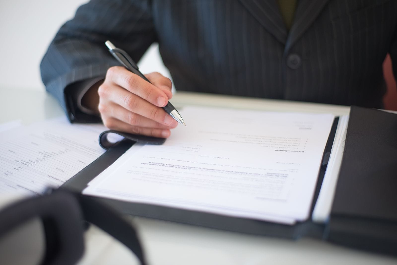 A person in a suit signing a franchise document on a clipboard