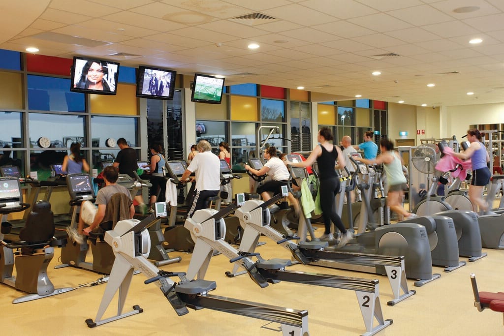A gym cardio area lined with treadmills and exercise machines