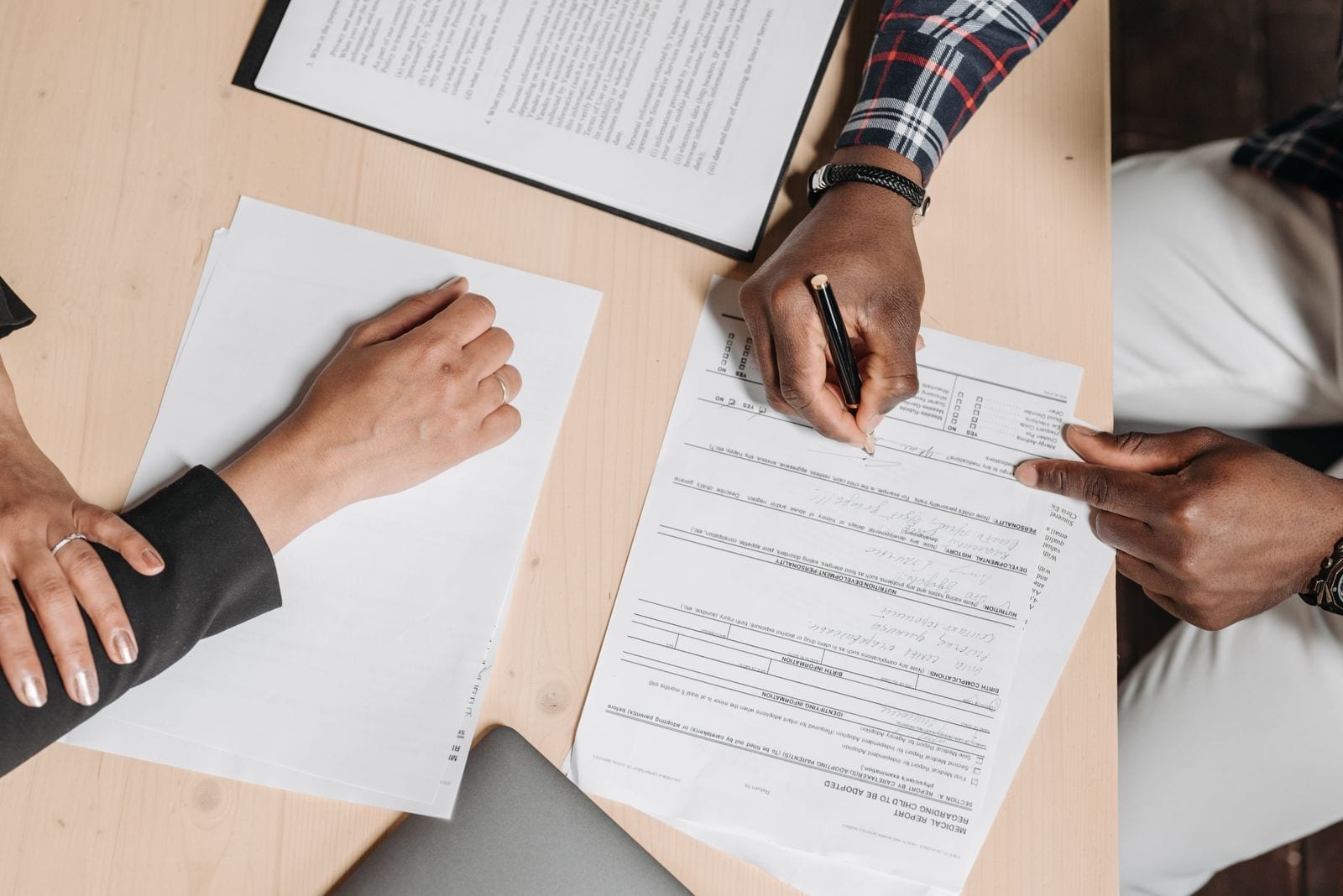 Two people signing documents at an office desk during a business meeting