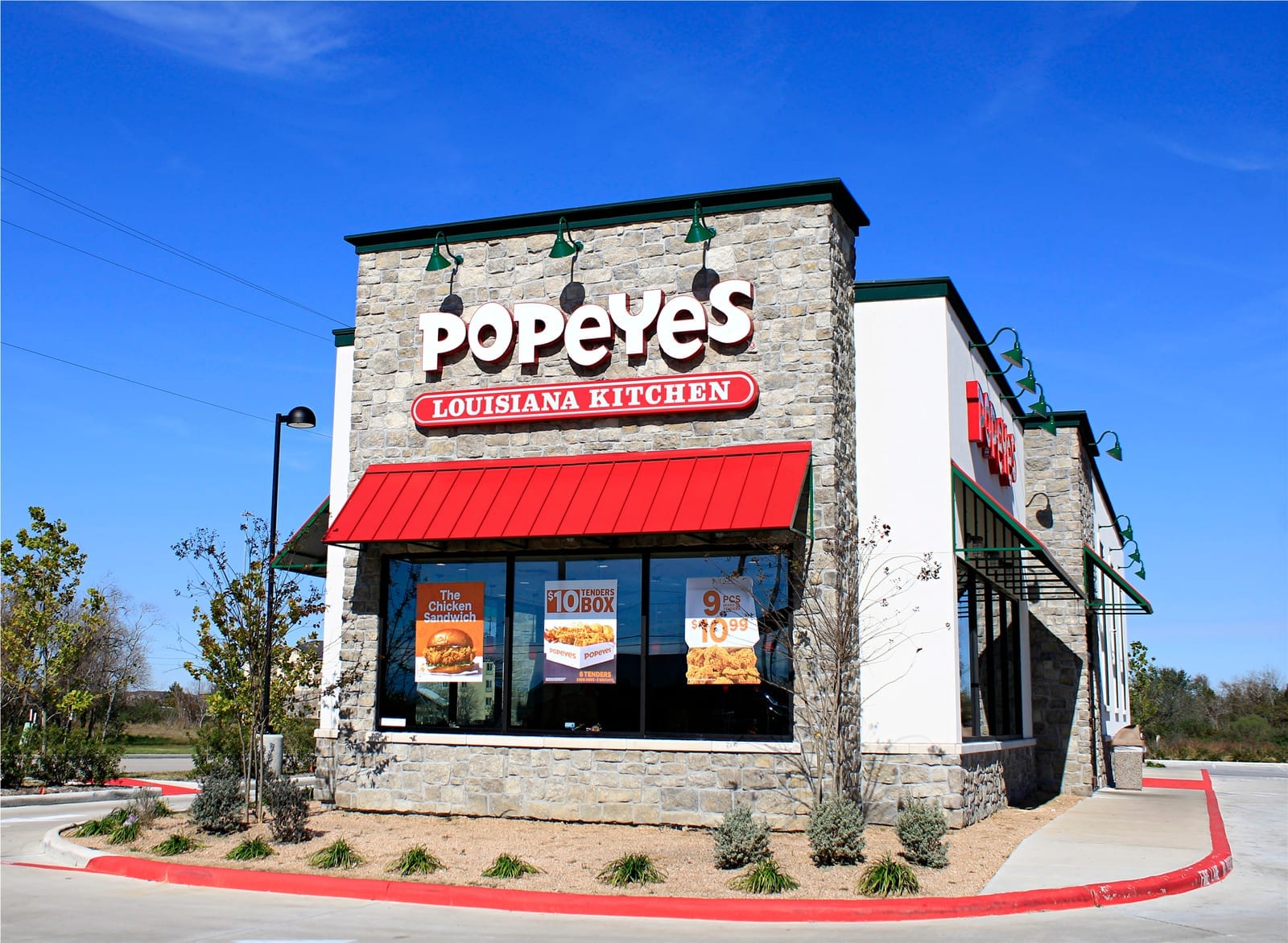 Popeyes restaurant exterior with signage and drive-thru along a commercial road in Houston, Texas