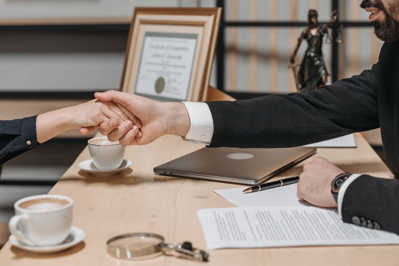 Two business partners shaking hands over a signed contract