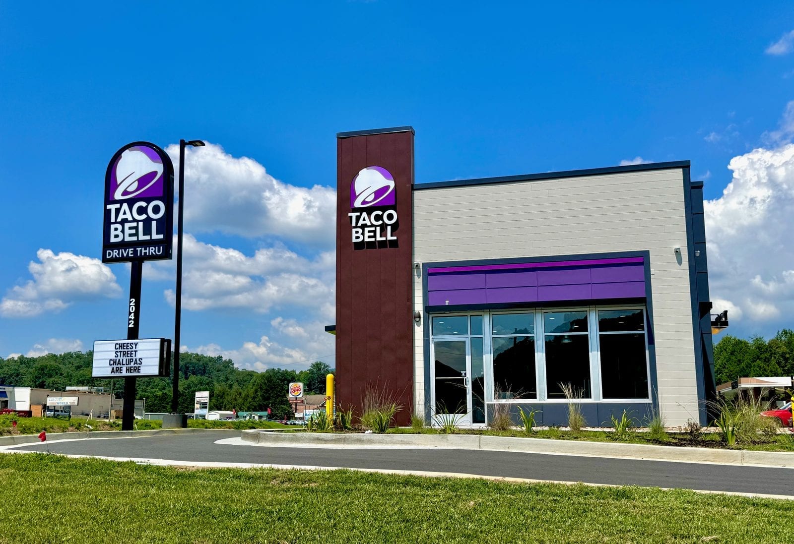 Modern Taco Bell restaurant exterior with drive-thru lane and purple bell signage