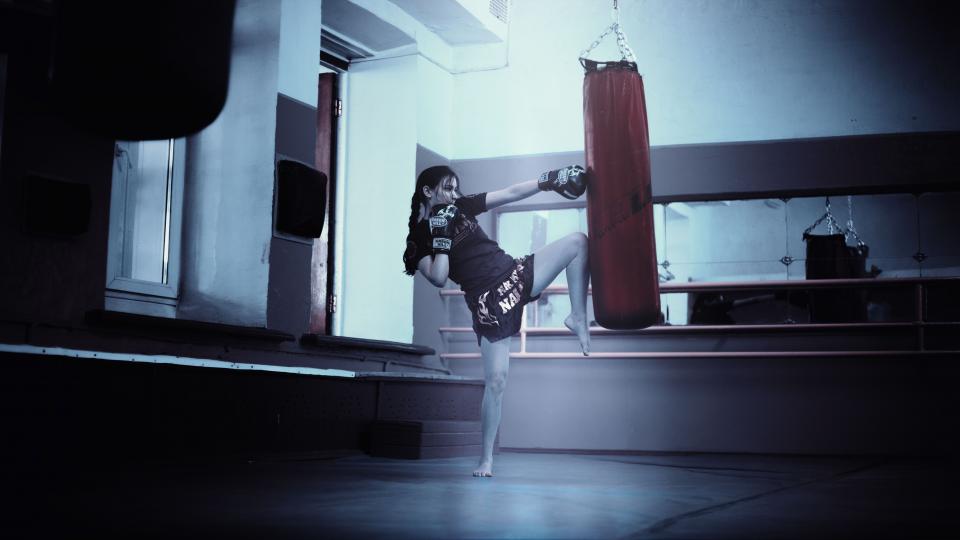 A person training kickboxing with focus mitts inside a combat-sports gym