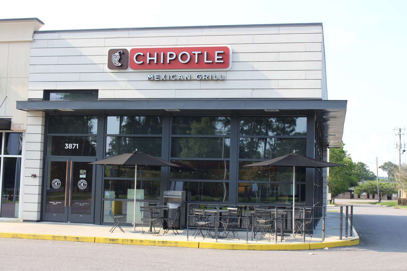Chipotle Mexican Grill storefront exterior with red-and-brown sign and outdoor patio seating